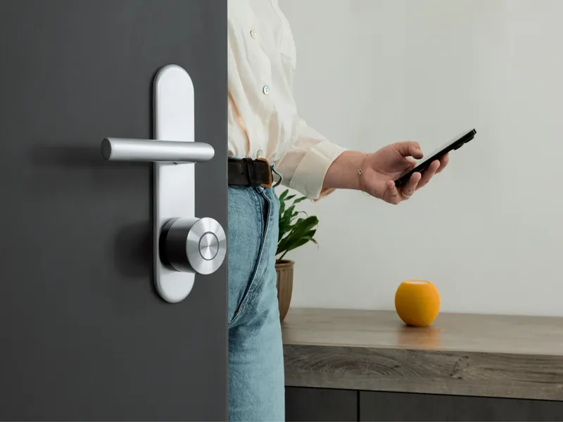 A person opening a door fitted with a Nuki lock using their phone