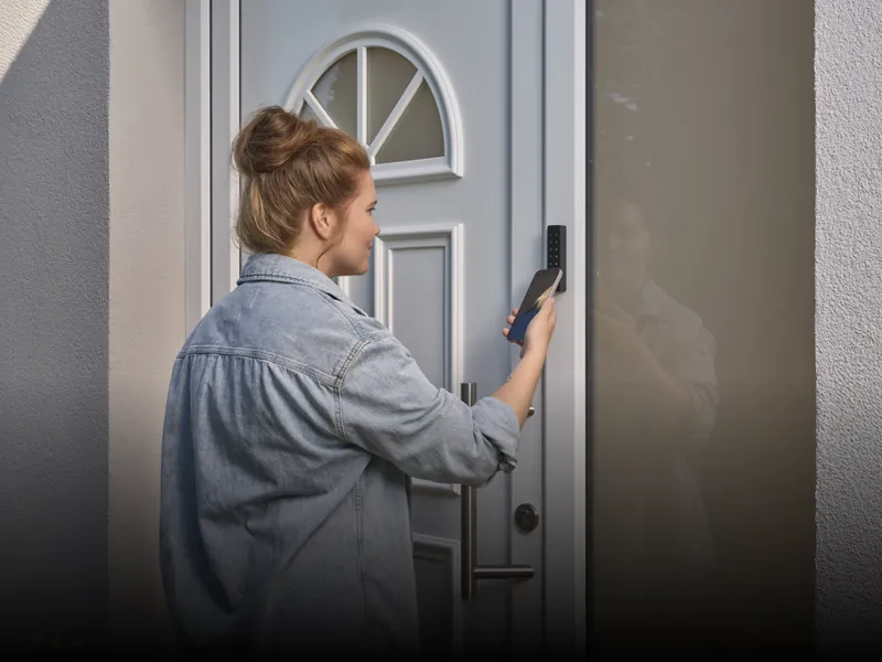 A woman typing her code on the Nuki keypad next to her door