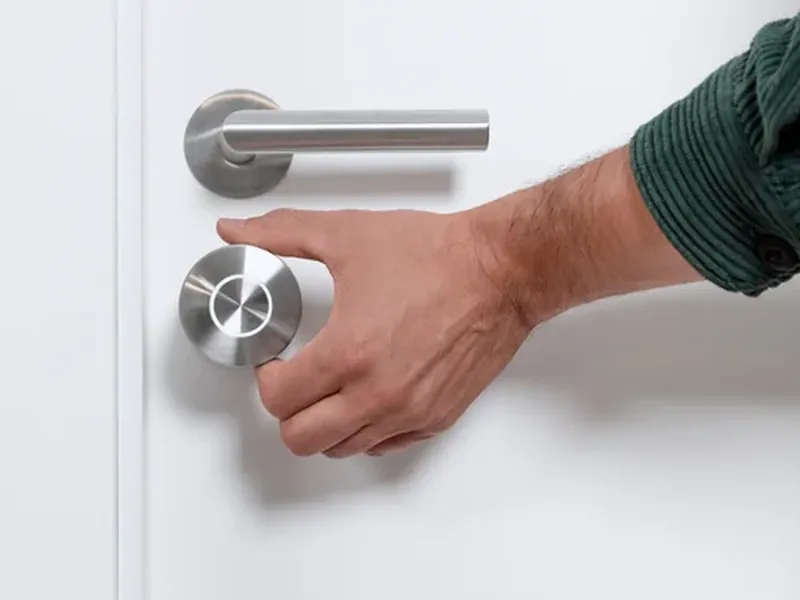 A hand turning the knob of the Nuki lock, on the inside of the door
